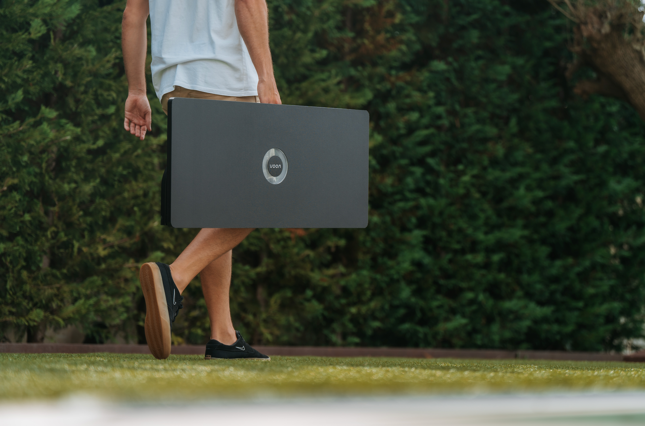 Father in a backyard carrying the Voon soccer smart rebounder for his kids to play and have fun.